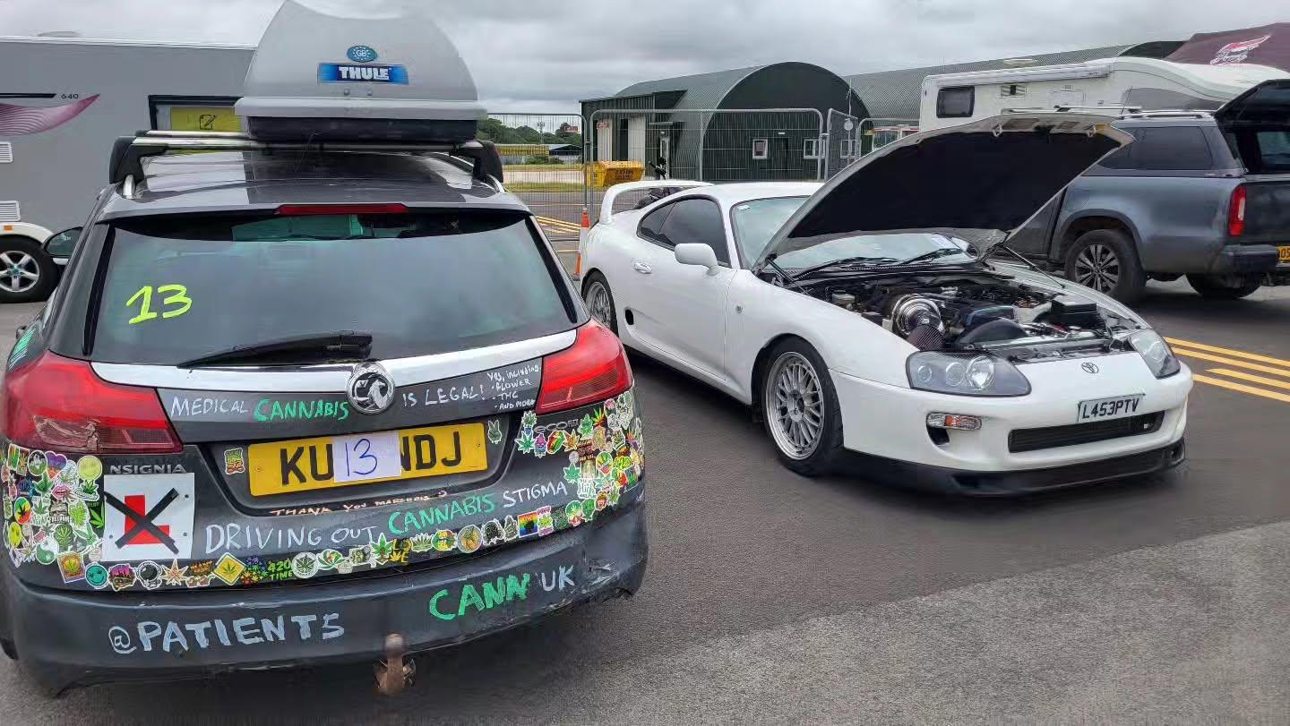 The Vauxhall Insignia estate with roof box in the paddock beside a white sports car