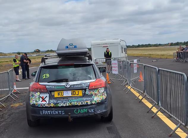 The rear of the liveried Insignia beside the barriers with a race trailer in the background